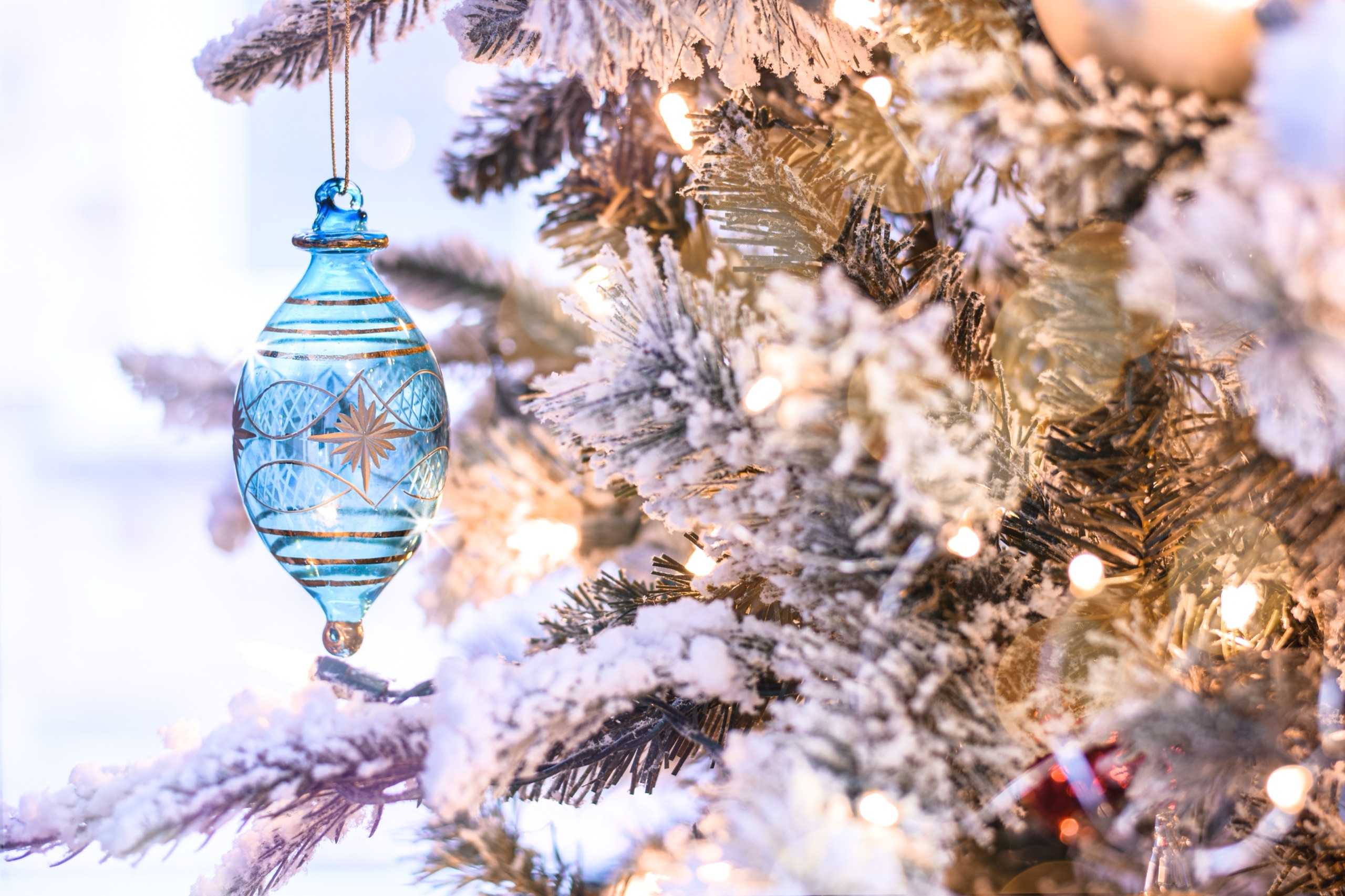 Glacier-blue glass ornament on a flocked branch